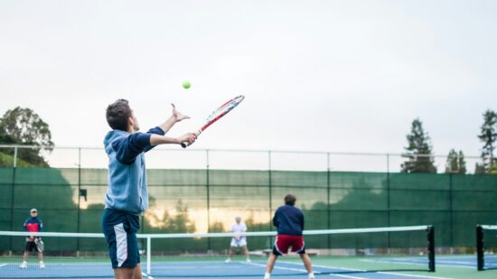 My friends playing a tennis match in the afternoon sun.